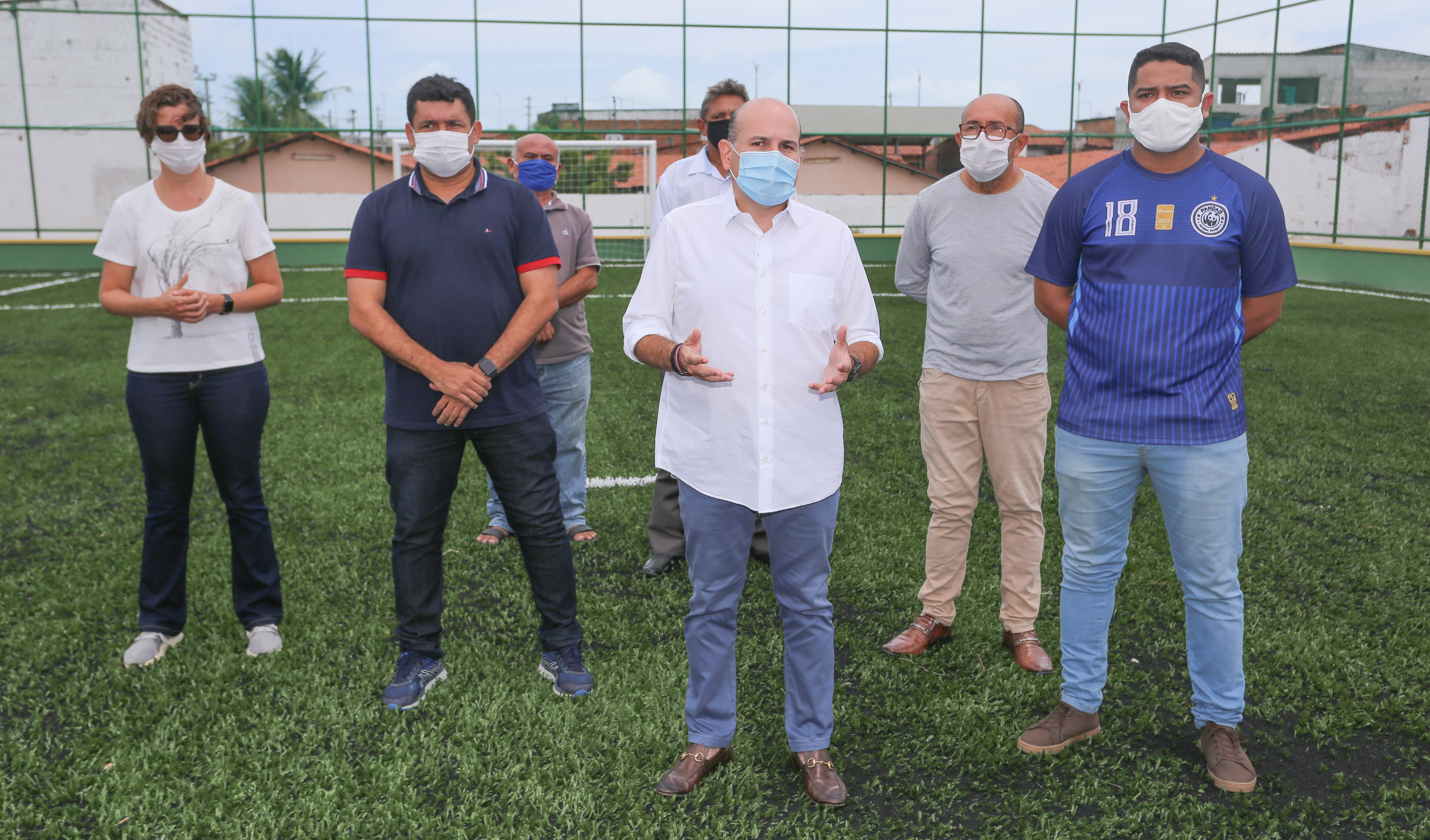 prefeito em pé com pessoas ao lado em campo de futebol, todos posando para a foto